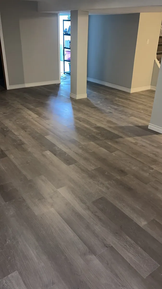 Grey plank flooring running across an open basement room after installation